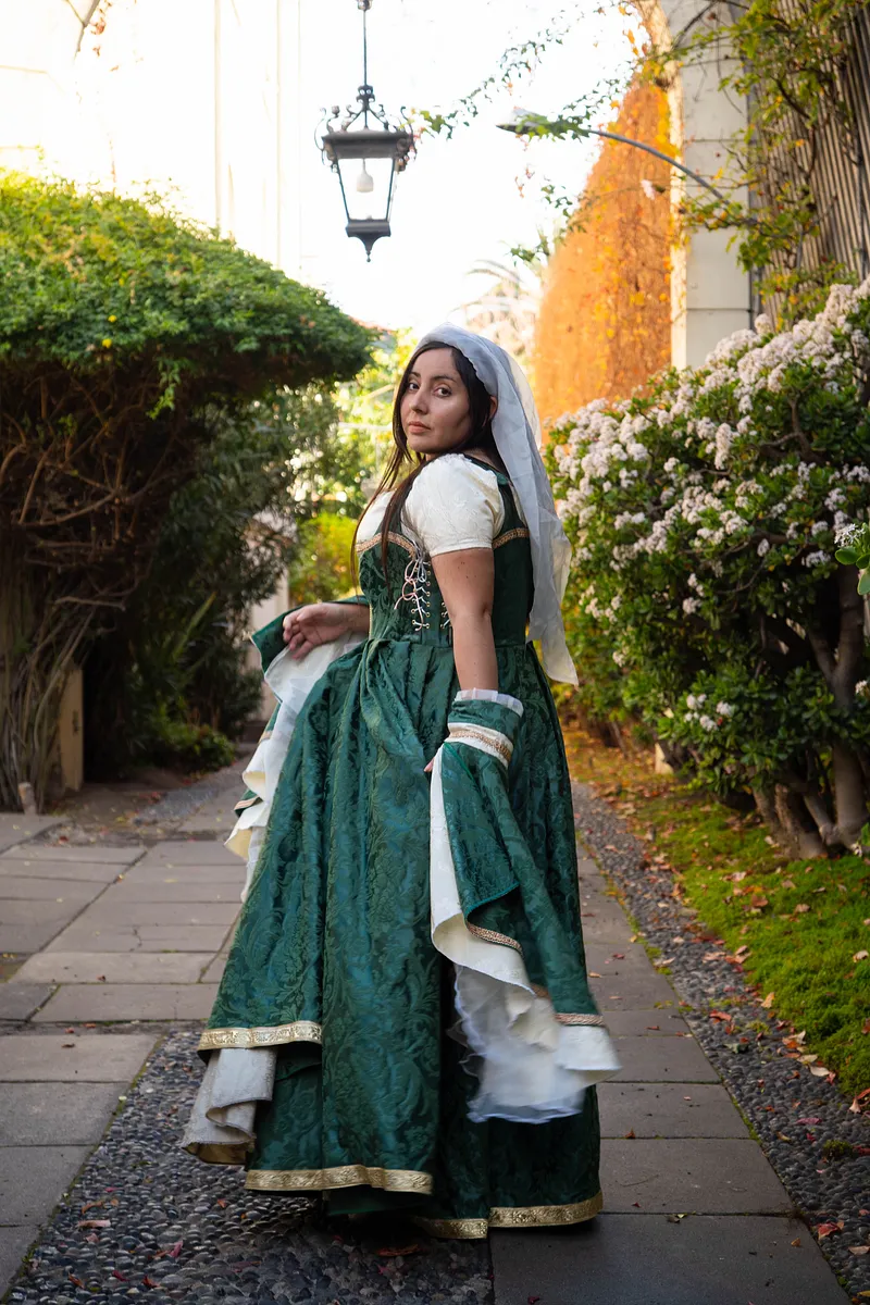 Vestido verde y dorado en un jardín de palacio, ideal para una corte feérica barroca.