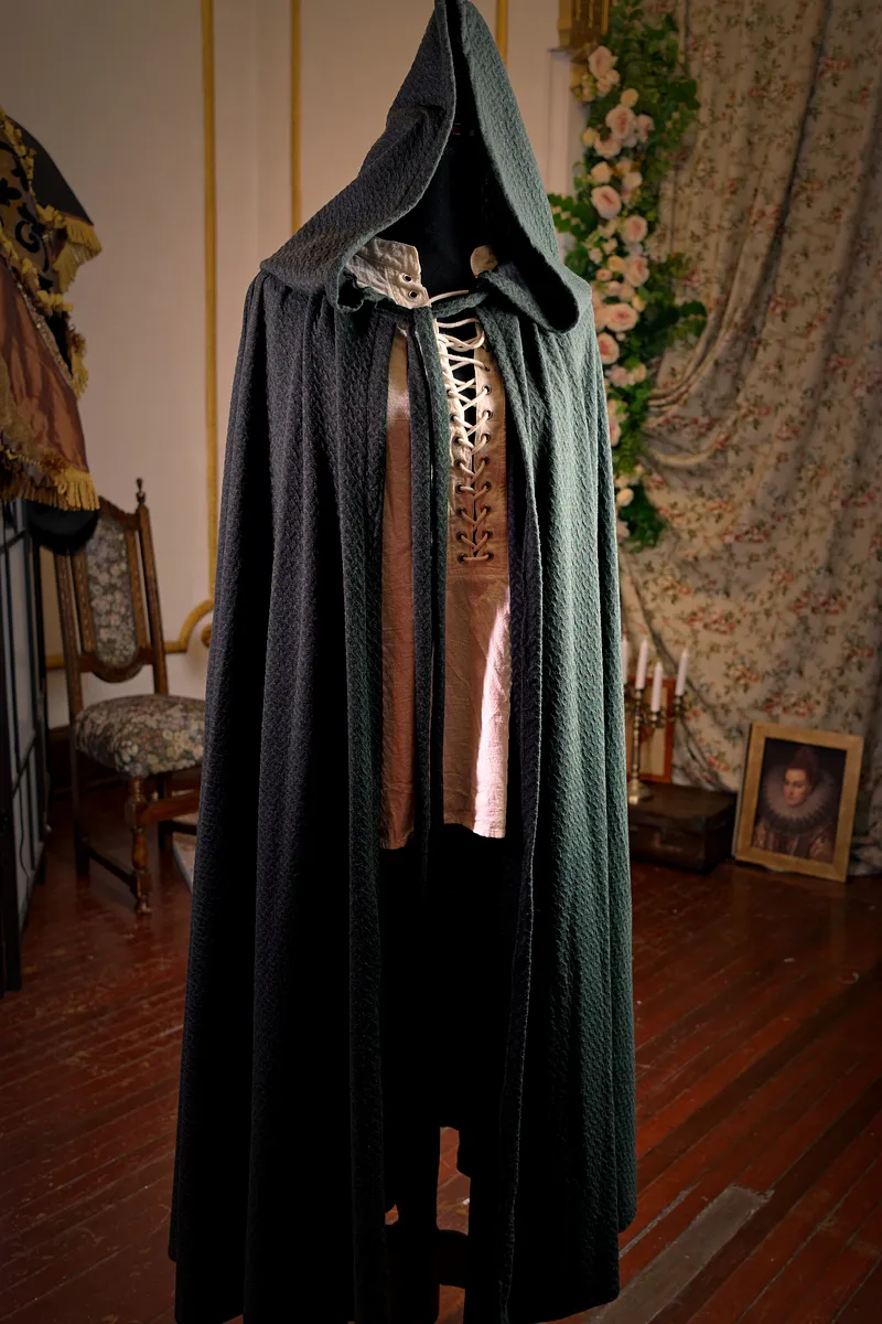 Frederick: capa larga verde oscuro con capucha, de inspiración medieval gótica.