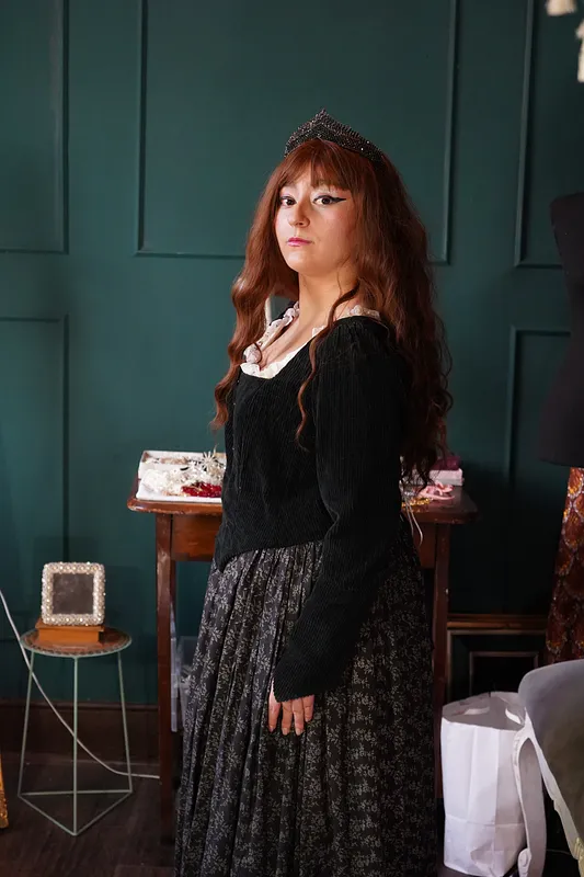 Vista lateral del vestido en uso, destacando la manga larga de textura acanalada, el perfil del cuerpo negro y la falda fruncida estampada.
