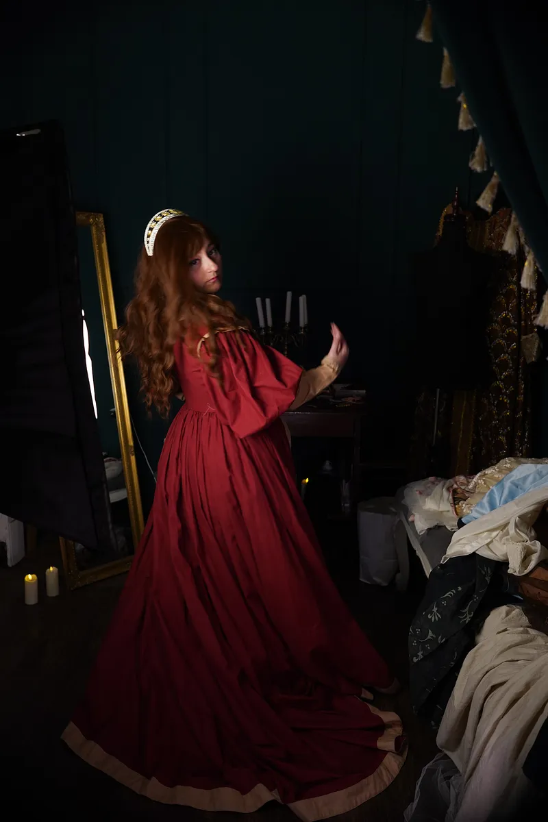 Vista de cuerpo completo en movimiento, con la falda roja extendida y cola amplia en un ambiente oscuro de estudio.