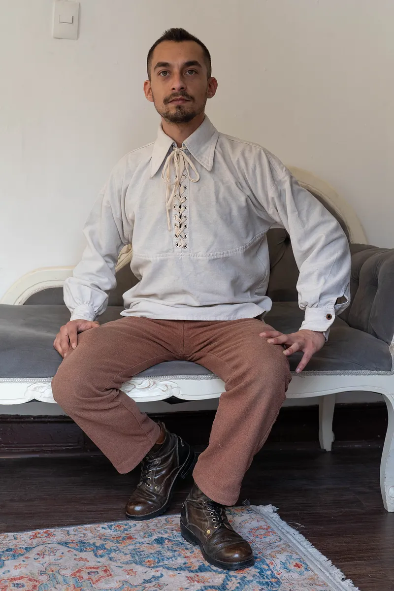 William (blusa) en color crema, con escote acordonado y mangas amplias, usada como base de un look masculino de fantasía histórica.
