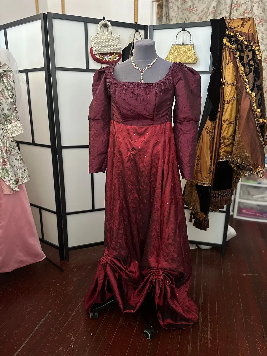 Karenina en borgoña, con mangas voluminosas, cintura marcada y falda amplia para una versión más dramática del baile histórico inspirado.
