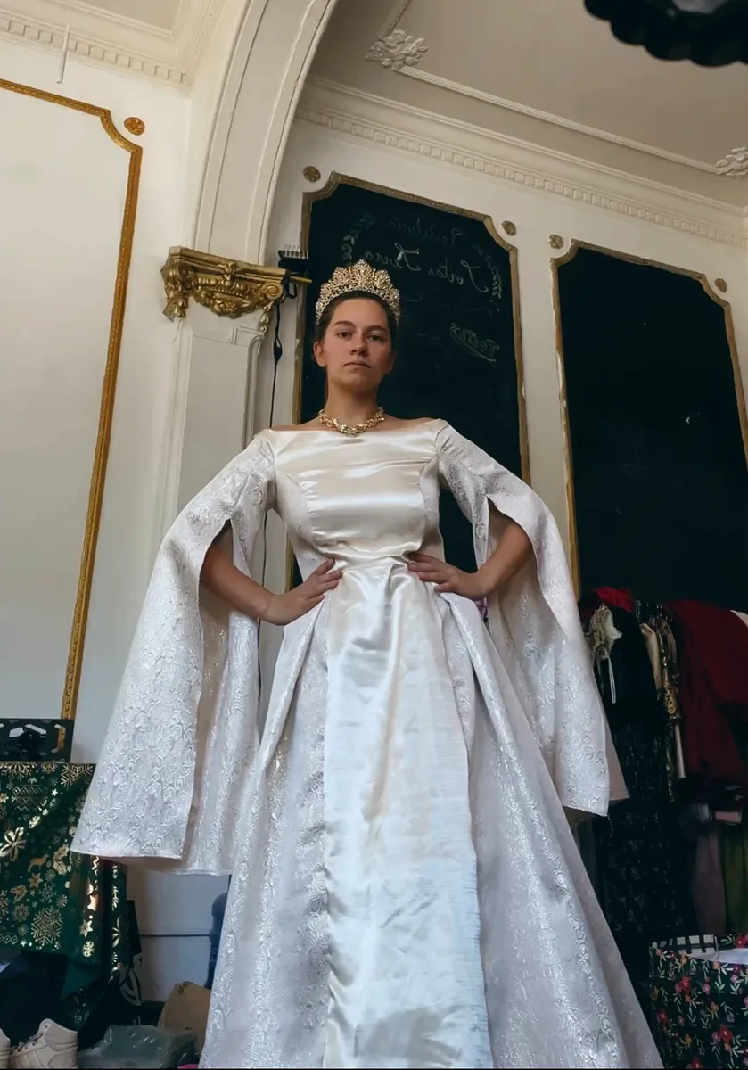 Reina en blanco, con falda amplia, mangas largas abiertas y corona, como ejemplo de fantasía palaciega no necesariamente rusa.