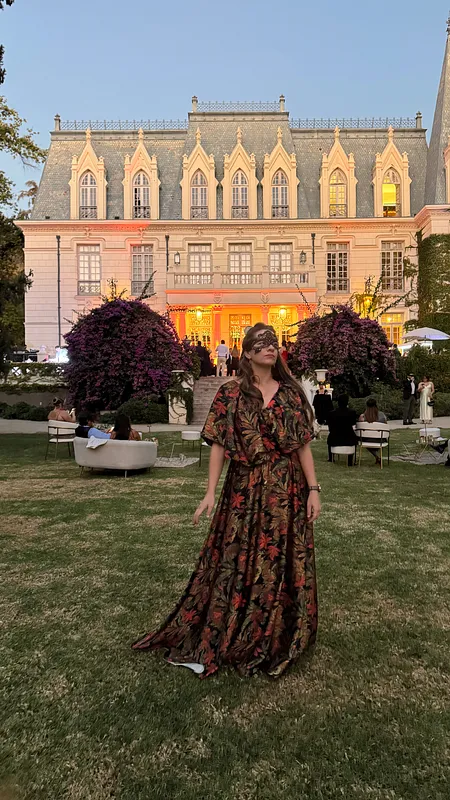 Vista completa al aire libre del vestido floral oscuro, con cuerpo ajustado, mangas voluminosas y falda larga extendida sobre el césped.