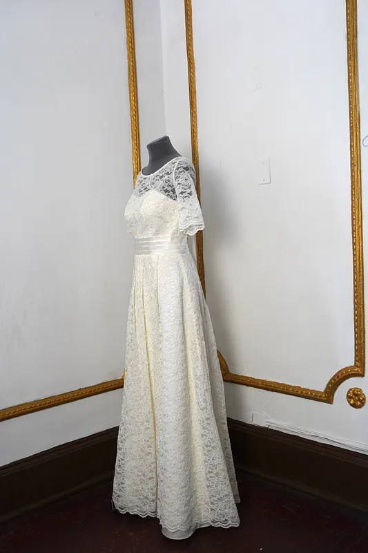 Vista lateral del vestido en maniquí, mostrando el cuerpo ajustado, la transparencia del encaje superior y la caída amplia de la falda.