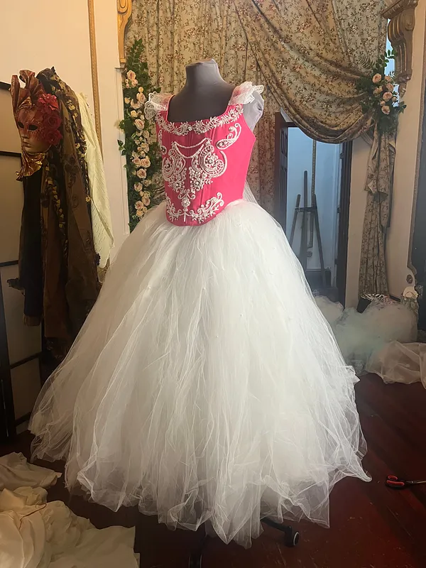 Vista completa en maniquí, con corpiño fucsia bordado en plateado y amplia falda blanca formada por numerosas capas de tul.