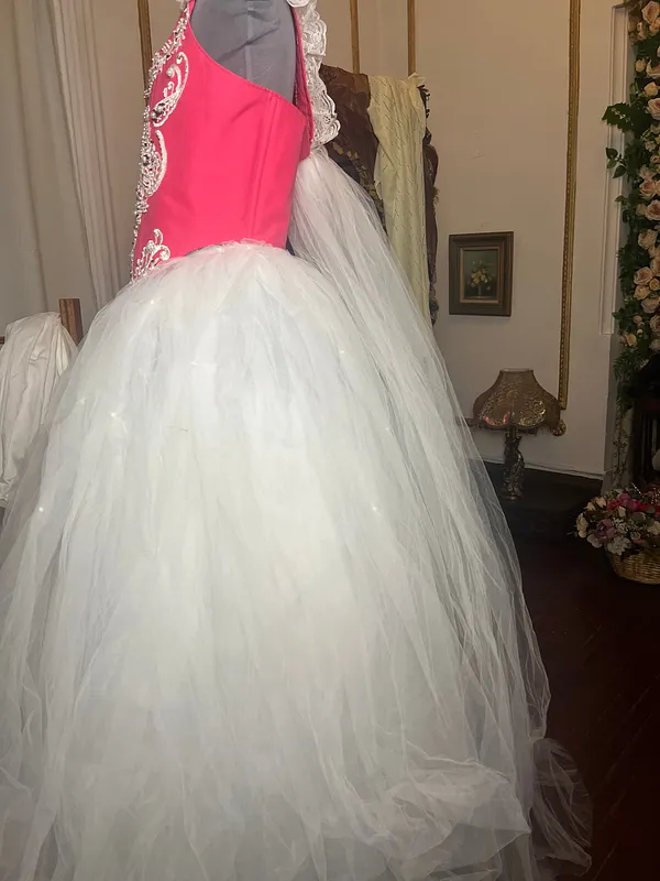 Acercamiento lateral del vestido, donde destacan el corpiño fucsia ajustado y el gran volumen de la falda blanca de tul.